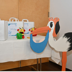 Storch mit Babygeschenken auf Tisch in Wien, Österreich, mit Stofftieren und Geschenktaschen.